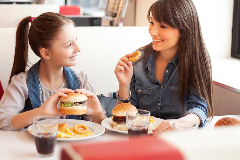mom and daughter eating in restaurant